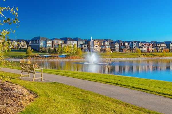 Walking path beside a pond and landscaped green space in Legacy, Calgary